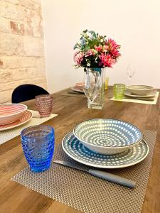 a table with plates and a vase with flowers at Iaru-Bed Experience House in Alberobello