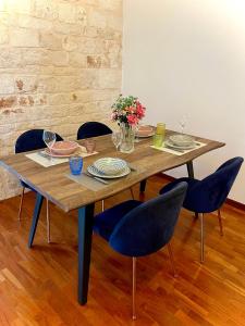 a wooden table with chairs and plates and flowers on it at Iaru-Bed Experience House in Alberobello