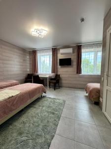 a bedroom with two beds and a table and a television at Hotel TETRIS Voznesensk in Voznesensk