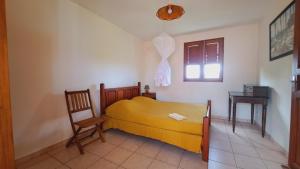 a bedroom with a bed and a chair and a window at Le Pavillon des Alizés in Gourbeyre