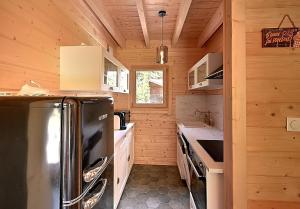 a kitchen with a black refrigerator and wooden walls at Chalet Caroubier - Chalet avec vue montagne in La Bresse +8 photos