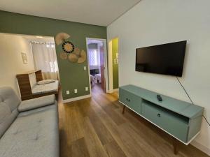 a living room with a couch and a television on a wall at Recanto Camburi in Vitória