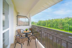 ein Balkon mit Tisch und Stühlen und einem Fenster in der Unterkunft Lulu Apartments - NoMoreRain - Apartament 2-pokojowy Grzybowo - klimatyzacja, Netflix in Grzybowo