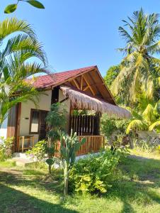 a guest house with a thatched roof and palm trees at Tangga Bungalows Gili Air in Gili Air