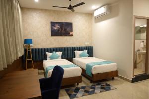 a hotel room with two beds and a chair at Zing Rooms by GuestHouse Suites in Bengaluru +21 photos