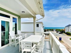 a white table and chairs on a balcony with the ocean at Shore Sounds Fun in Surf City