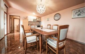 LisičićiにあるAwesome Home In Lisicic With Wifiのダイニングテーブルと椅子、そして壁に掛けられた時計