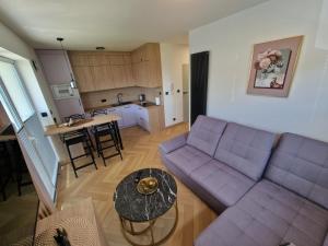 Una sala de estar con un sofá morado y una mesa. en Kropla w morzu 1, en Darłowo