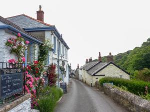 eine leere Straße in einem kleinen Dorf mit Blumen in der Unterkunft Little Barn Cottage in Portloe