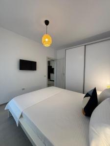 a bedroom with a large white bed and a flat screen tv at Velvet Breeze Apartment in Năvodari +1 photo