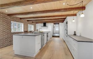 a kitchen with white cabinets and a brick wall at Lovely Home In Ringkøbing With Wifi in Klegod