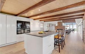 a kitchen with white cabinets and a bar with stools at Lovely Home In Ringkøbing With Wifi in Klegod