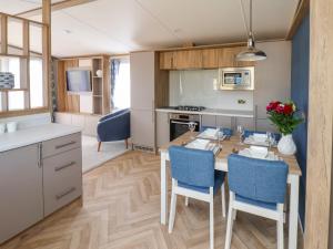 a kitchen with a wooden table and blue chairs at Aspen Lodge in Whitby +25 photos