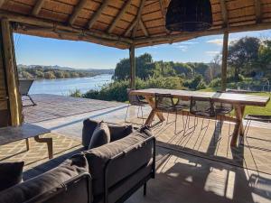 a patio with a table and chairs and a view of a river at Tzamenkomst River Lodge in Colesberg