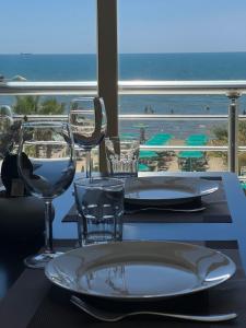 a table with wine glasses and a table with a view of the beach at Wave Beachfront Apartments in Durrës