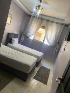 um pequeno quarto com duas camas e uma janela em Appartement Artisanale em Salé