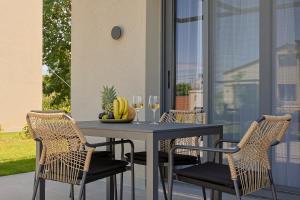 a table with chairs and a bowl of fruit and wine glasses at Dream Olympus Mare Seaside Pool Villas in Olympic Beach