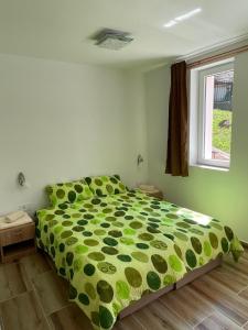 1 dormitorio con 1 cama con edredón verde y ventana en Vazdušna Banja Okean Ljubavi, en Soko Banja