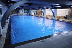 a large swimming pool with blue water in a building at Zing Rooms by GuestHouse Suites in Bengaluru