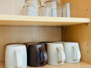 a row of coffee mugs sitting on a shelf at Spacious flat in Streatham in London +3 photos