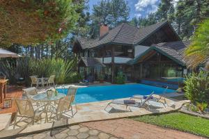 a house with a pool and a table and chairs at Pousada Cantos e Contos in Monte Verde