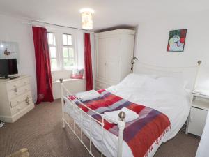 een slaapkamer met een wit bed en rode gordijnen bij Kestrel Cottage in Keswick