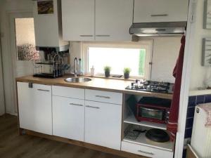 a small kitchen with white cabinets and a sink at Hundefreundliches Chalet Meise in Wervershoof