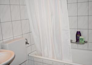 a white bathroom with a shower curtain and a sink at Ruhiger Vorort Bern kostenloses Parken 6km Zentrum in Zollikofen +15 photos