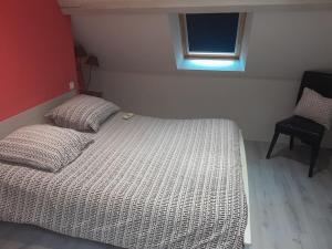 a bed in a bedroom with a window and a chair at Maison a côté du pal in Saligny-sur-Roudon