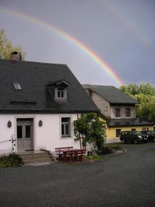 a rainbow over a white house with a picnic table at Hammerschloss Unterklingensporn in Naila