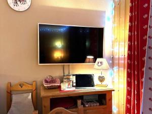 a television on a wall with a table with a laptop at Chalet rénové 6 pers avec WIFI et parking gratuit à La Joue du Loup - FR-1-504-128 in Le Dévoluy