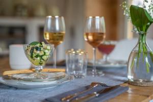 a table with two glasses of wine and a vase with a flower at Hygge Lodge Annecy in Doussard