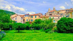un groupe de bâtiments dans un parc avec des arbres dans l'établissement Vale's Gardens at Borgio Verezzi, à Borgio Verezzi
