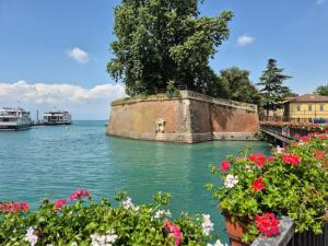 Un viejo muro de piedra en el agua con flores. en Lake Garda relax, en Peschiera del Garda