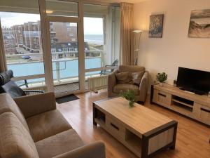 ein Wohnzimmer mit einer Couch, einem Fernseher und einem Tisch in der Unterkunft het Zeehuisje in Egmond aan Zee