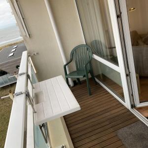 ein Balkon mit einem grünen Stuhl auf einer Veranda in der Unterkunft het Zeehuisje in Egmond aan Zee