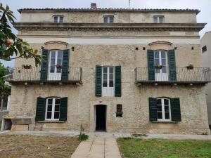an old building with green shuttered windows and a door at B&B Don Antonio in Civitella Casanova