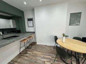 eine Küche mit einem Holztisch, Stühlen und einer Theke in der Unterkunft Staywell Hartlepool in Hartlepool