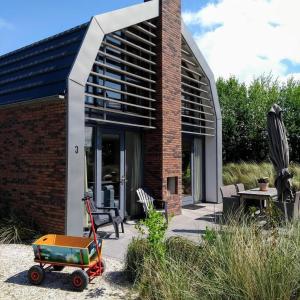 una casa de ladrillo con un carro delante de ella en Villa Duinhuis Zee, en Egmond aan den Hoef