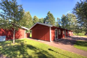 un edificio rojo con un árbol delante de él en Rättviks Golfby, en Rättvik