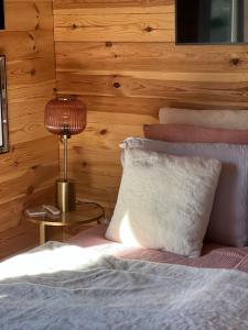 a bedroom with a bed with a lamp and pillows at Hygge Lodge Annecy in Doussard
