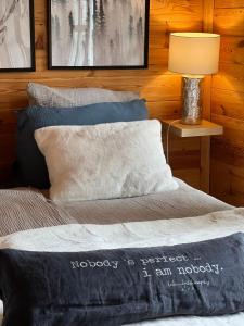 a bedroom with a bed with two pillows and a lamp at Hygge Lodge Annecy in Doussard