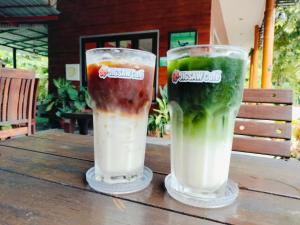 two drinks sitting on top of a wooden table at Jigsaw Cafe & Resort in Ban Na We