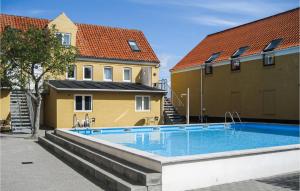 a swimming pool in front of two buildings at Stunning Apartment In Gudhjem With 1 Bedroom, Outdoor Swimming Pool And Wi-Fi in Gudhjem +8 photos