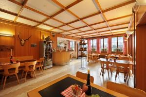 - un grand salon avec des murs en bois, des tables et des chaises dans l'établissement Gasthaus Paxmontana, à Sachseln