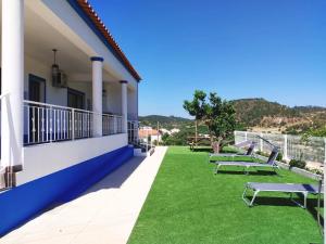 ein Balkon eines Hauses mit grünem Gras und Bänken in der Unterkunft Familia Sequeira in São Bartolomeu de Messines