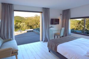 Un dormitorio con una cama y una gran puerta corrediza de vidrio. en Les lofts de palombaggia, en Porto Vecchio 48 fotos más