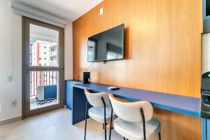 a blue desk with two chairs and a television on a wall at 360 Mirant Vila Madalena in Sao Paulo