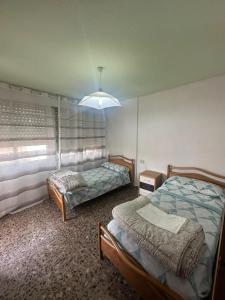 a bedroom with two beds and a chandelier at Apartamento Dúplex vacacional in Burriana +11 photos