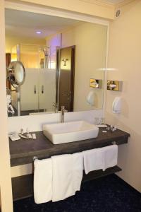 a bathroom with a sink and a large mirror at Grand Hotel Empire in Frankfurt/Main